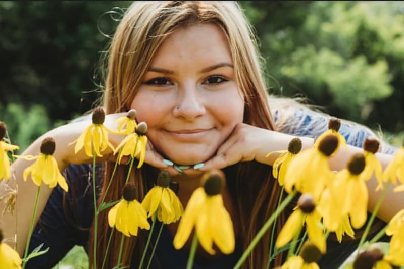 A smiling woman amongst a field of yellow flowers